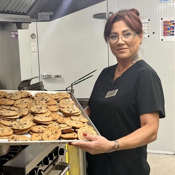 A woman holding a tray of chocolate chip cookies