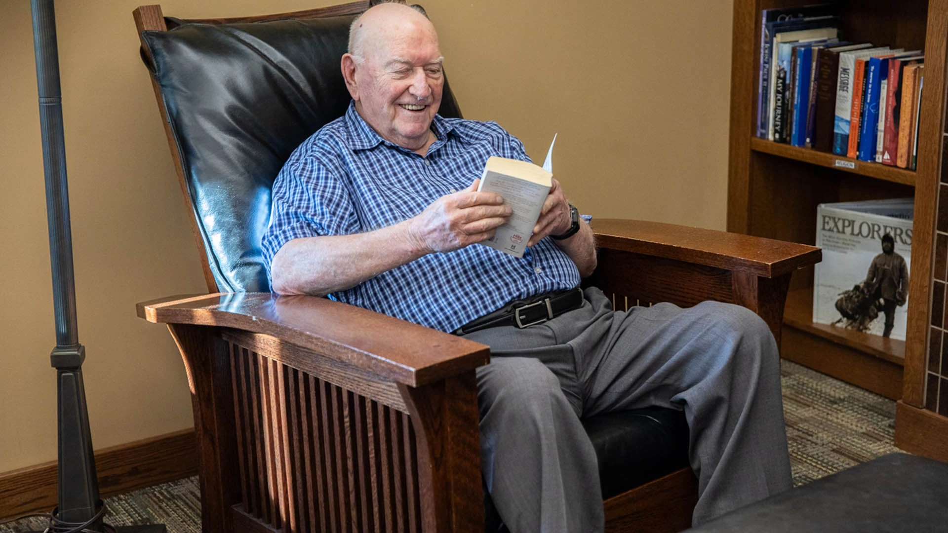 Senior male sitting in brown chair reading