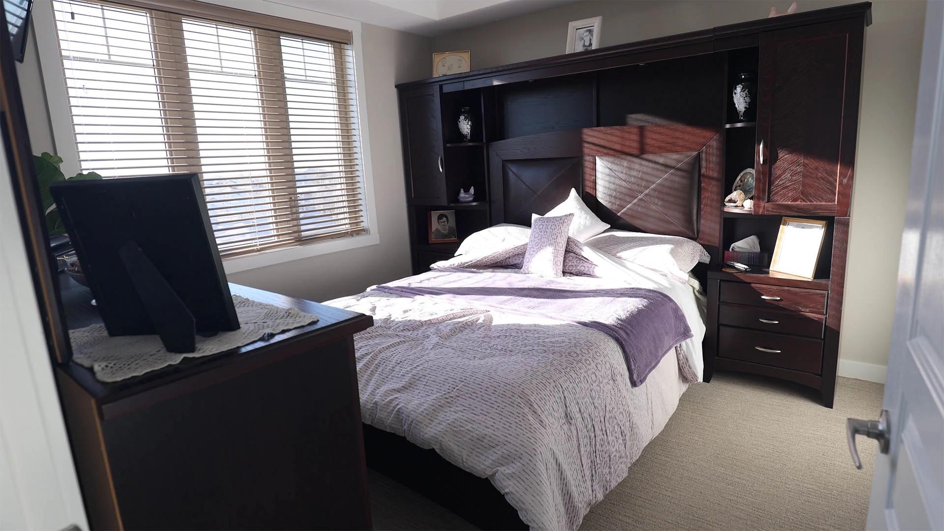 Bedroom with dark brown furniture and white and purple bedding