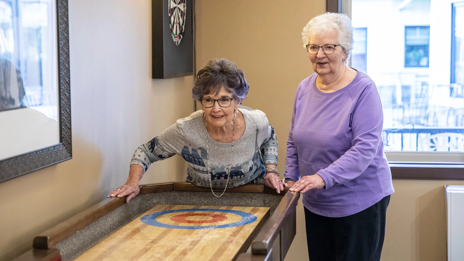Two female seniors playing shuffle board.